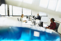 Two women and a man are working on their desk. They having a conversation.