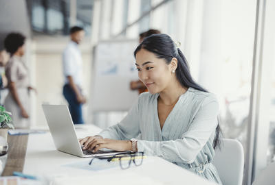 Photo of a woman working on her laptop in an office.