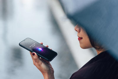 Woman using voice assistant on smartphone in the rain 