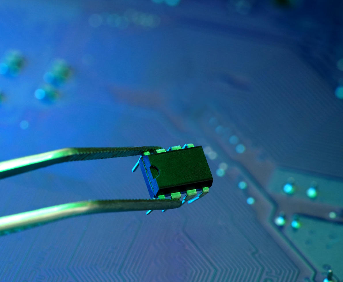 Tweezers hold a microchip with circuit background and copyspace